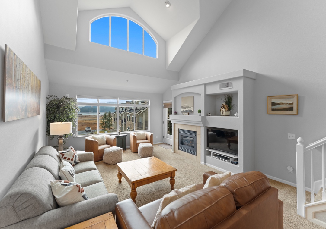 Relax in your spacious living room with soaring ceilings, cozy fireplace, and stunning lake views through expansive windows.