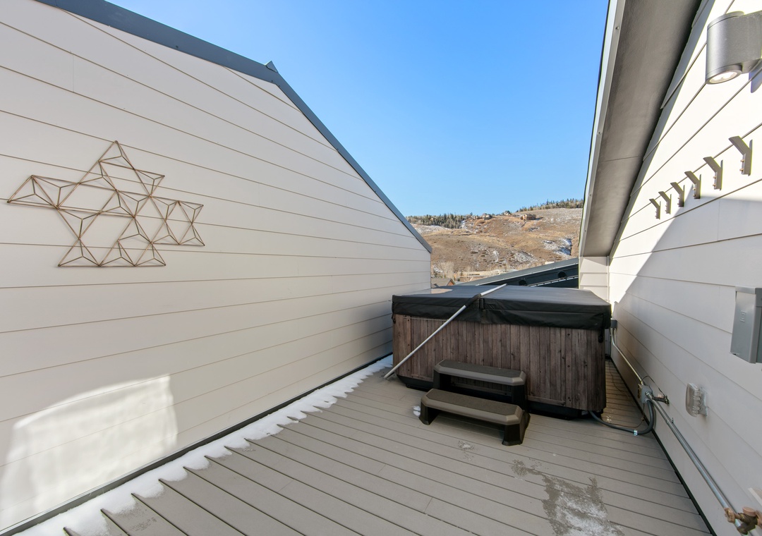 Soak in your private hot tub on this mountain-view deck, where geometric wall art adds charm to your alpine retreat.