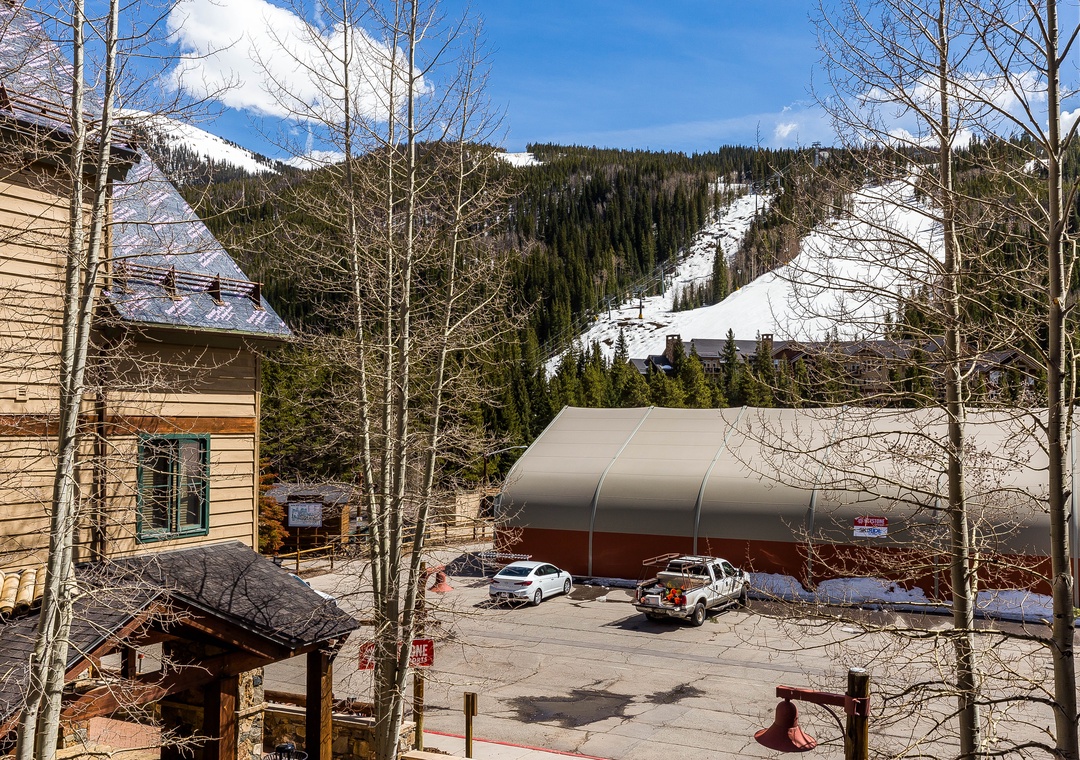 Snow-covered mountain slopes and ski runs frame this alpine village setting with convenient parking facilities.