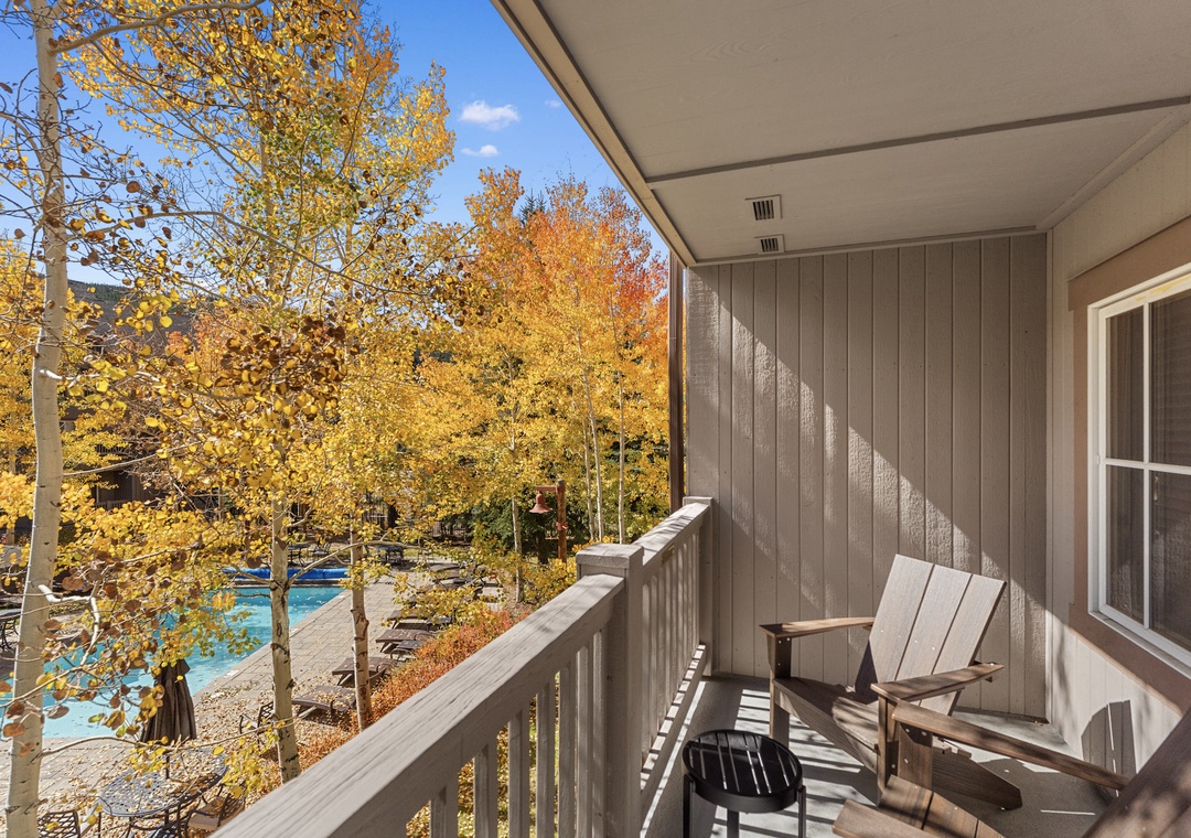 Your private balcony overlooks vibrant autumn trees and the sparkling pool below, perfect for morning coffee or evening relaxation.