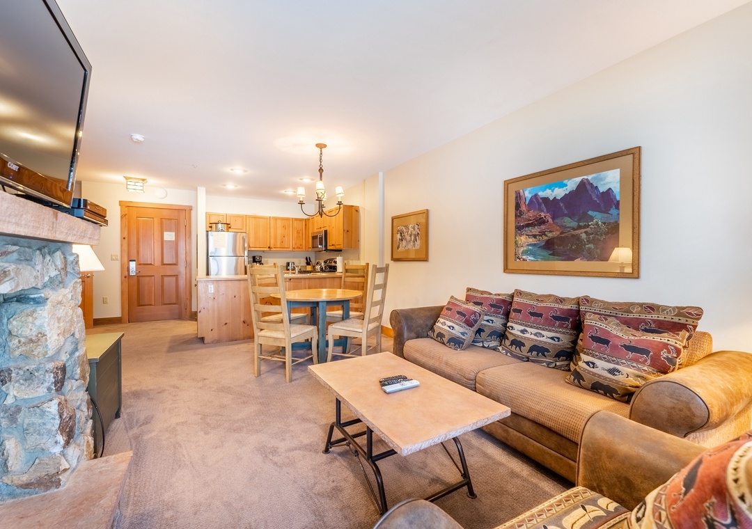 Cozy open-concept space with stone fireplace, mountain art, and rustic charm creates your perfect mountain retreat sanctuary.