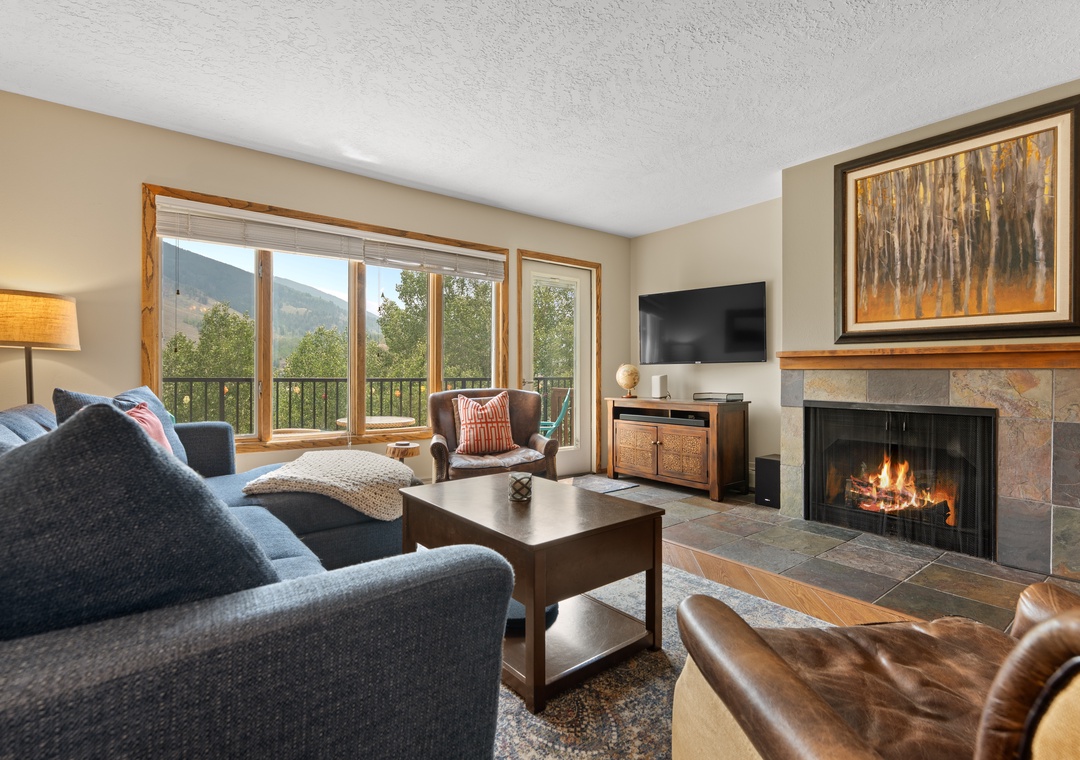 Cozy up by your stone fireplace with mountain views framing the windows. This inviting living space offers plush seating, warm ambiance, and a peaceful retreat after your adventures.