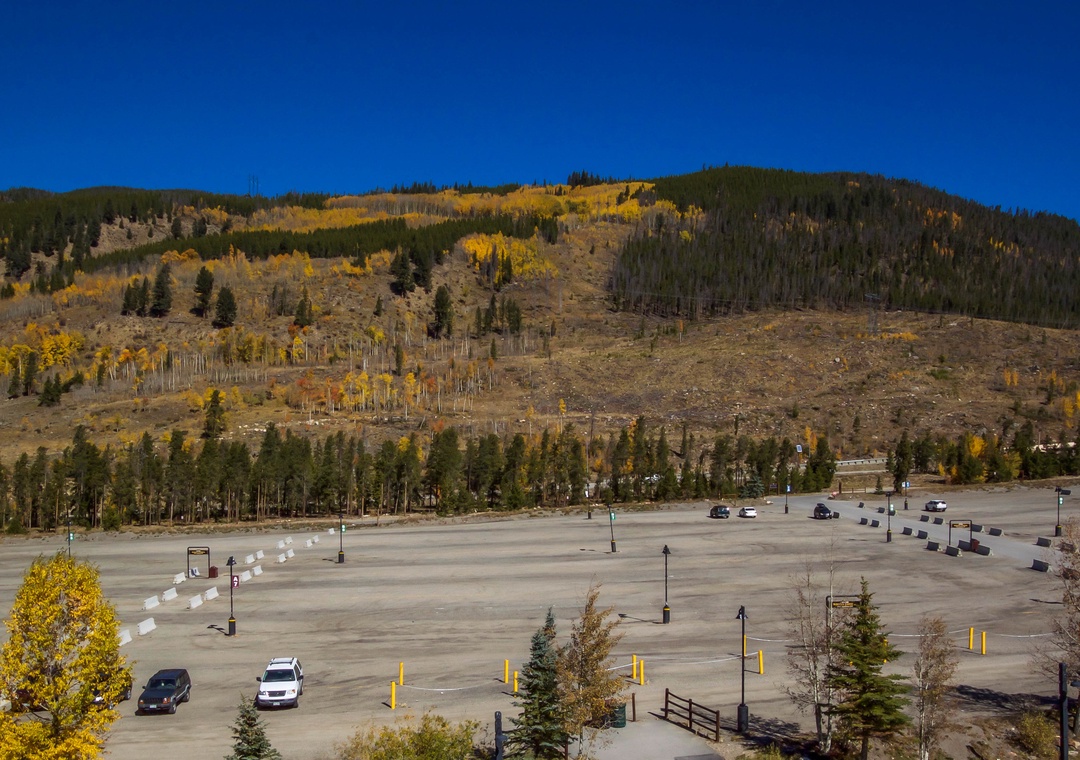 Expansive parking area surrounded by stunning autumn foliage and mountain views in a scenic mountain town setting.