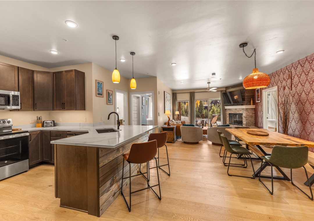 Step into your stylish open-concept haven where gourmet cooking meets cozy gatherings, featuring rich wood cabinetry and warm pendant lighting.
