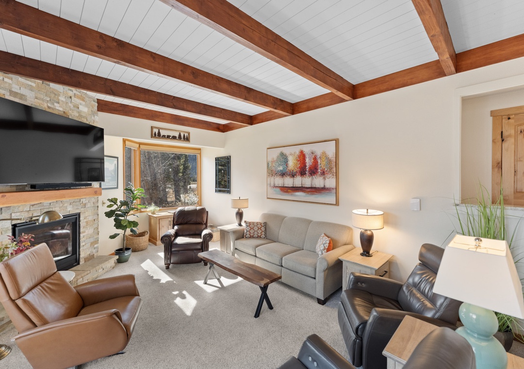 Unwind in your stylish living room with exposed wood beams, crackling fireplace, and plush seating perfect for cozy evenings together.