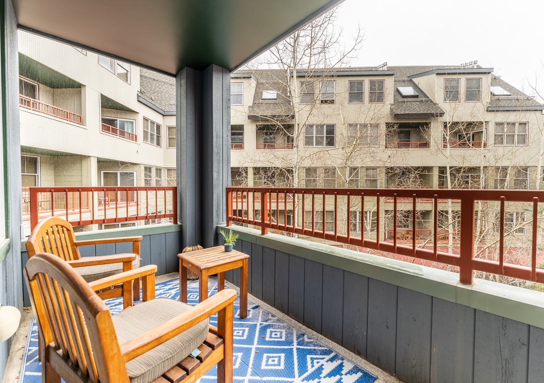 Your private balcony awaits with comfortable wooden chairs and a small table—perfect for morning coffee while overlooking the quiet neighborhood.