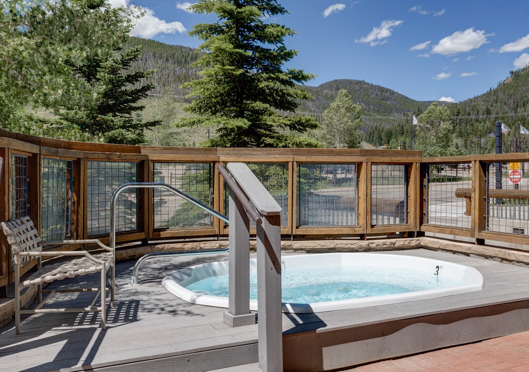 Soak in the warm waters while gazing at forested mountain peaks under clear blue skies—a perfect outdoor retreat.