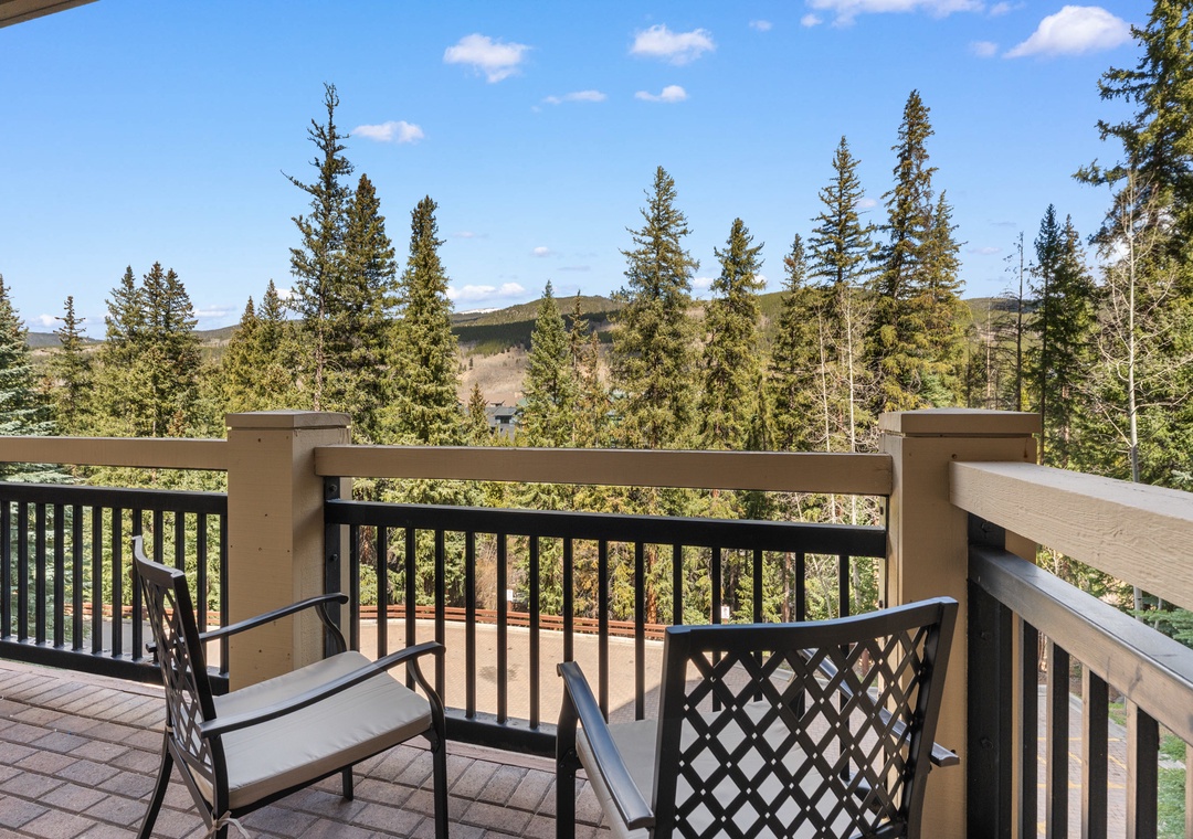 A private deck framed by towering evergreens and rolling mountain terrain, offering a peaceful spot to unwind with morning coffee or evening relaxation.
