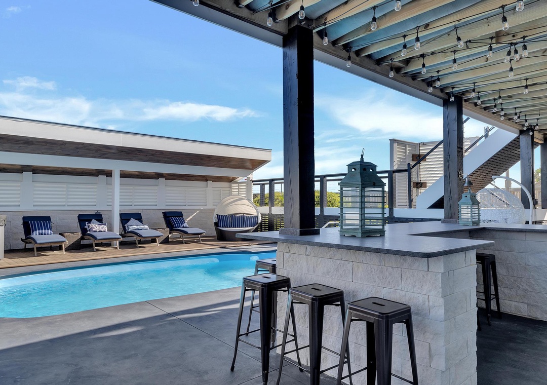 Unwind poolside under the pergola, where bar seating invites you to sip drinks while soaking in blue skies and sparkling water views.