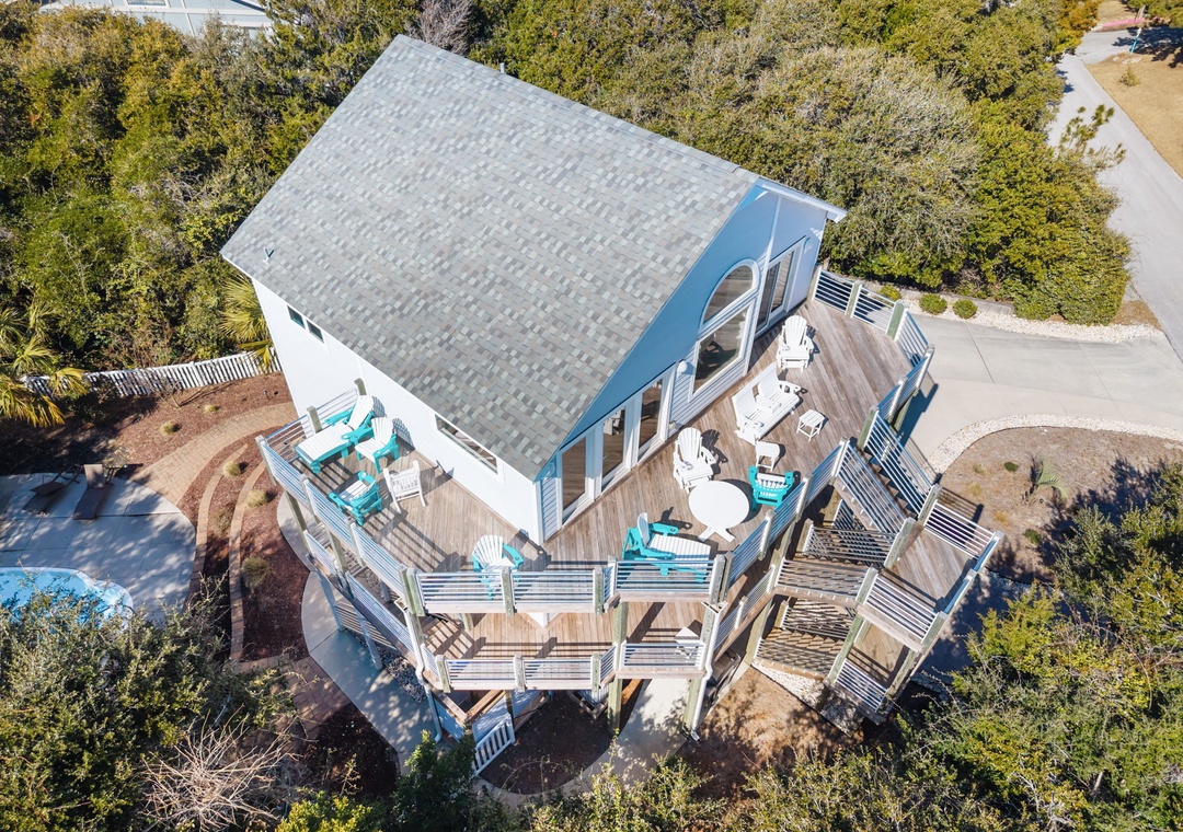 Elevated coastal home features multiple deck levels with turquoise outdoor seating and natural surroundings.