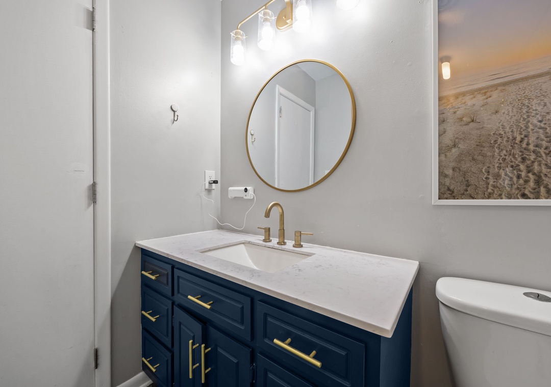Refresh in your elegant bathroom with marble countertops, brass fixtures, and crisp coastal artwork.