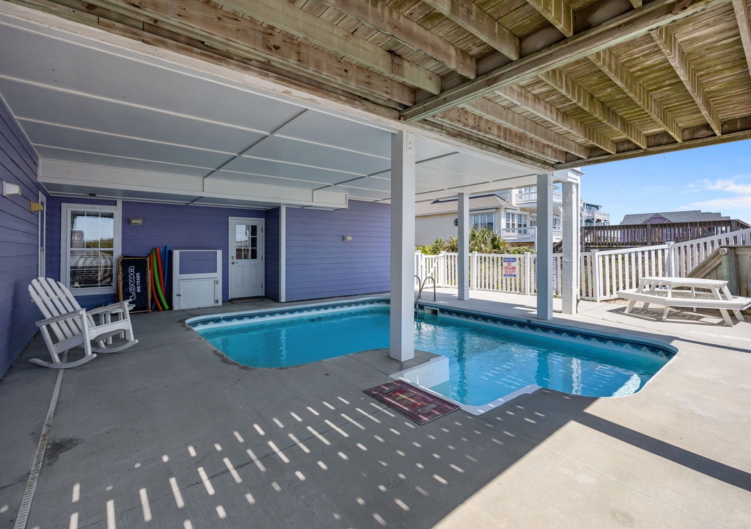 Dive into your private oasis with this covered pool deck, perfect for swimming and lounging while staying shaded from the sun.