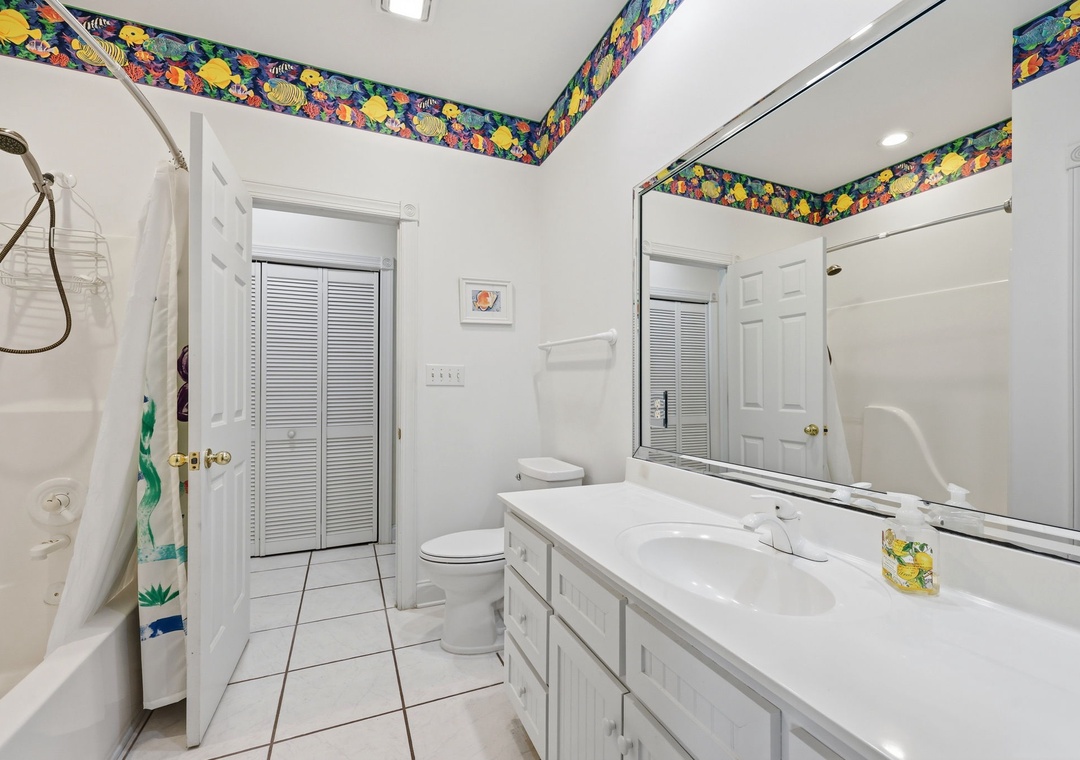 Bright bathroom with cheerful tropical accents, dual sinks, and a tub-shower combo—your refreshing retreat after a day of island adventures.