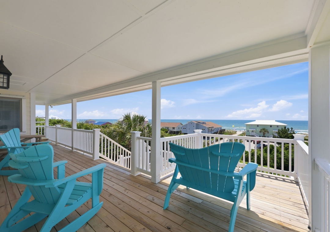 Your covered porch offers a stunning seaside retreat with turquoise Adirondack chairs framing breathtaking ocean views, perfect for morning coffee or sunset cocktails in coastal comfort.