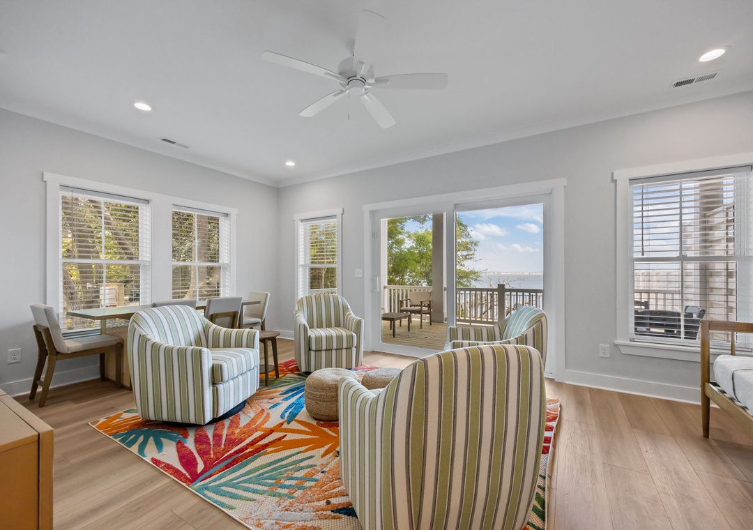 Relax in your bright living space with striped seating, colorful rug, and French doors opening to your private deck with scenic views.