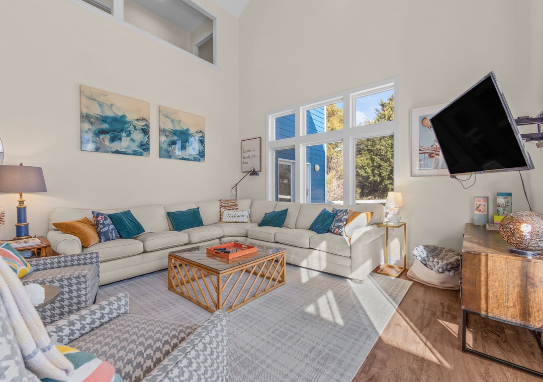 Relax in your spacious living room with plush sectional seating, natural light streaming through large windows, and modern entertainment setup for cozy evenings.