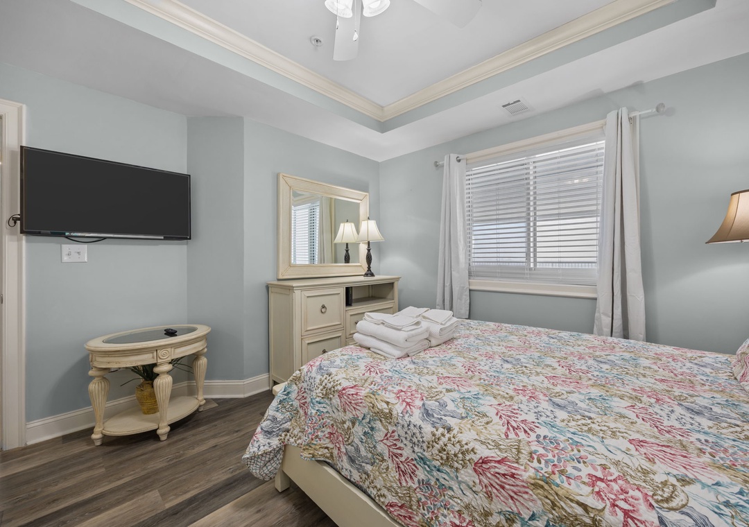 Sink into your comfortable bed in this serene bedroom where soft morning light filters through blinds, creating the perfect atmosphere for restful sleep.