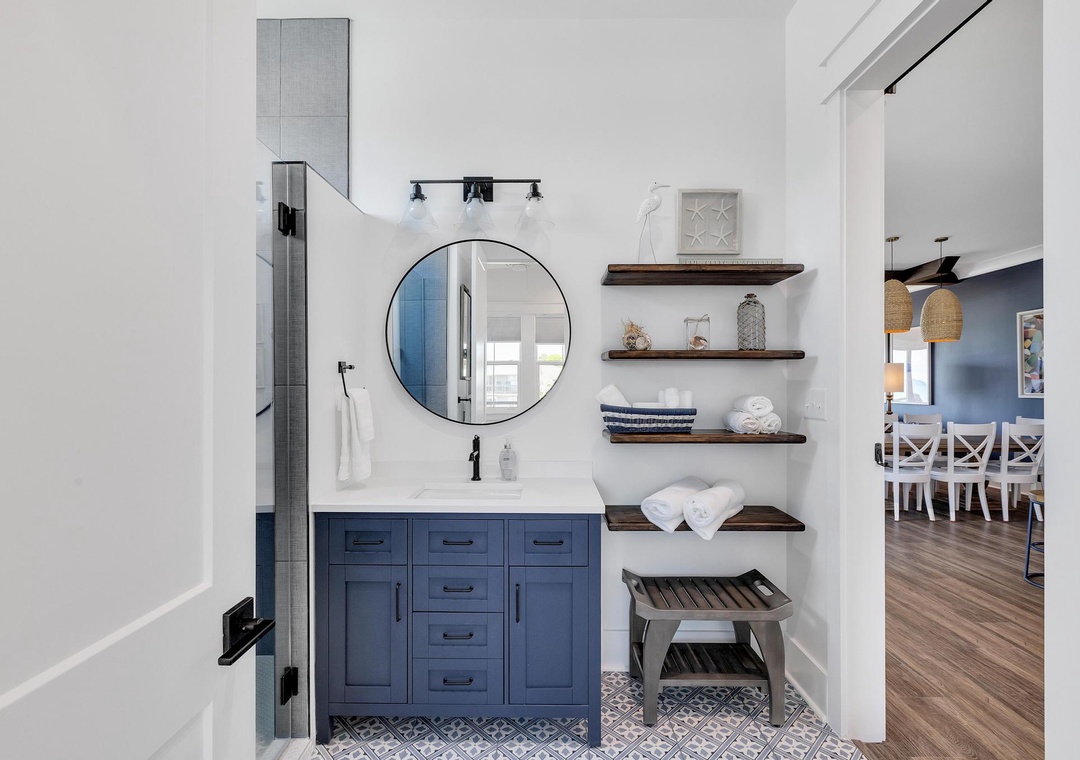 Your stylish bathroom features crisp white subway tile, a spacious vanity with coastal navy cabinetry, and soft towels waiting on open shelving to make you feel right at home.