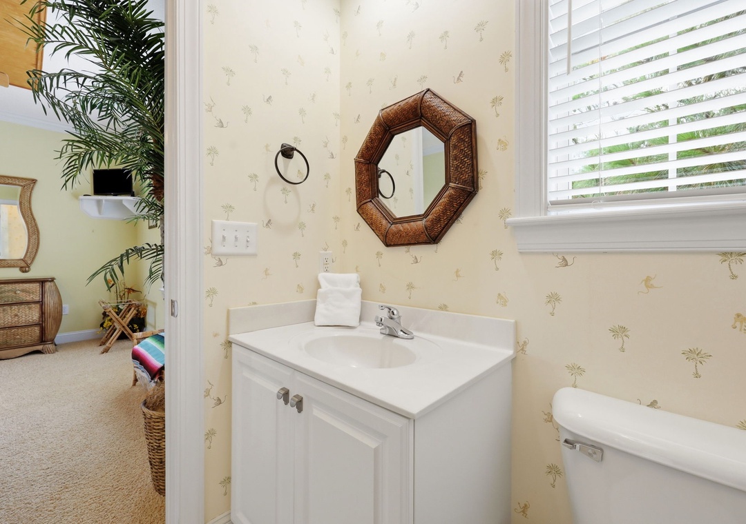 Freshen up in your private bathroom featuring charming coastal wallpaper, a clean vanity, and fluffy towels. Natural light adds warmth and a welcoming touch to your daily routine.
