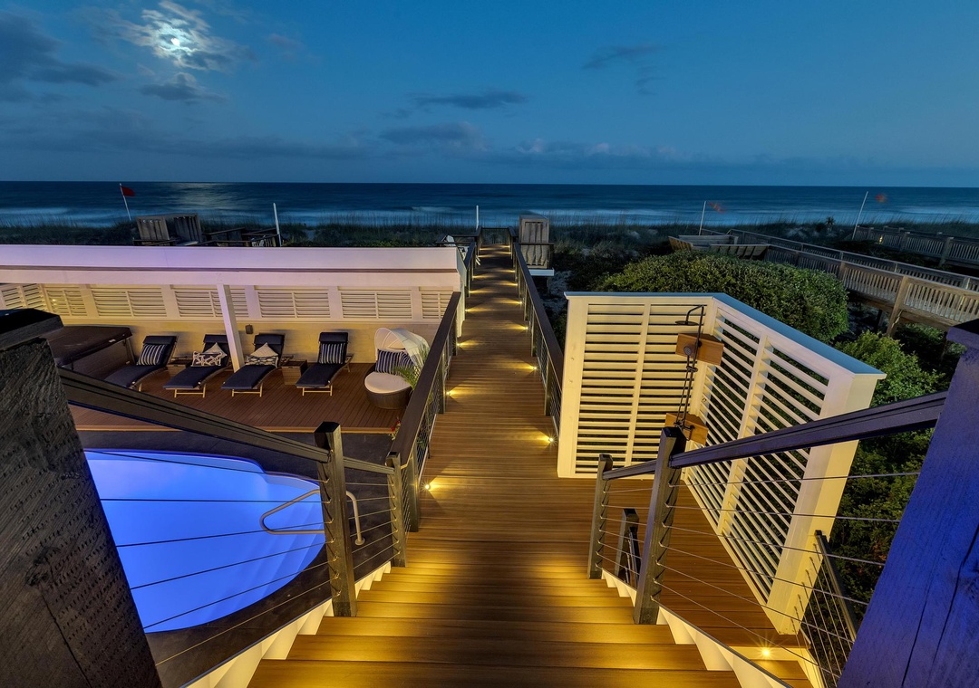 Spectacular rooftop deck showcasing breathtaking ocean views, illuminated steps, stylish lounge seating, and a glowing pool—perfect for unwinding under twilight skies.