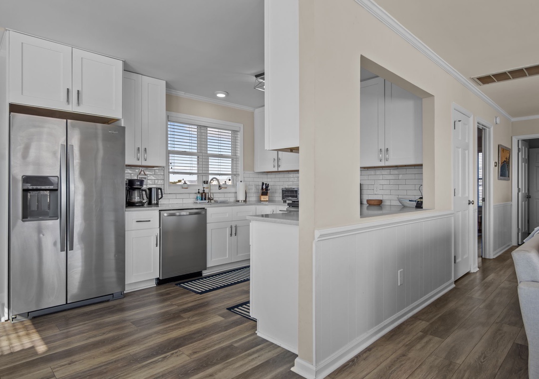 Your fully equipped kitchen awaits with modern appliances, crisp white cabinets, and a convenient breakfast bar for morning coffee.