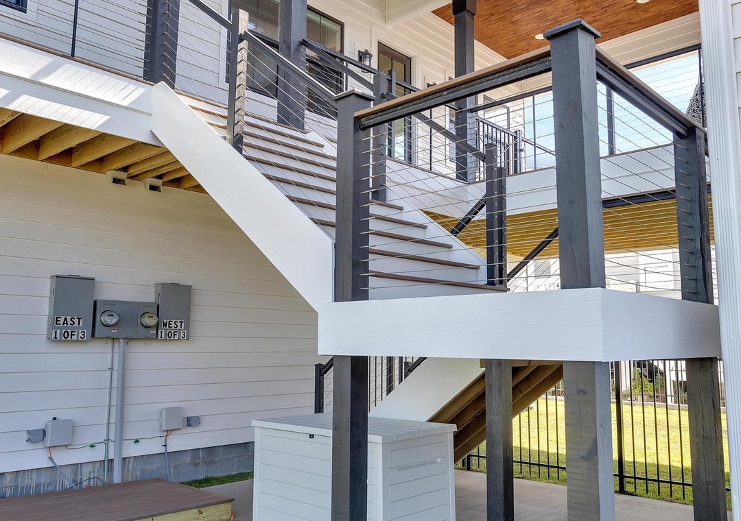 Modern coastal architecture featuring a two-story structure with warm wood ceilings, sleek cable railings, and covered outdoor spaces on raised stilts—ideal for beachside living.