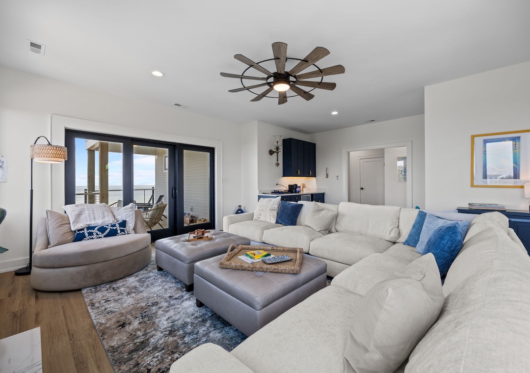 Your spacious living room features a plush sectional sofa perfect for gathering, with ocean views through sliding glass doors.