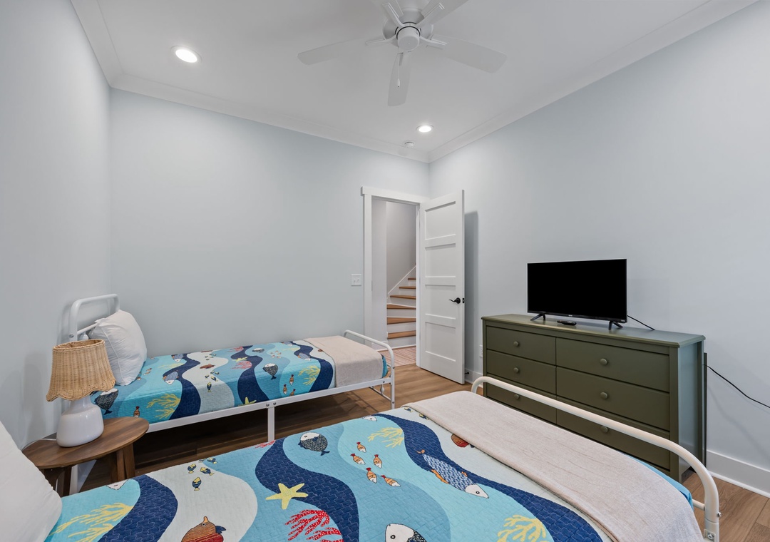 You'll love the fun ocean-themed bedding in this bright bedroom, perfect for kids with twin beds and a TV for movie nights.