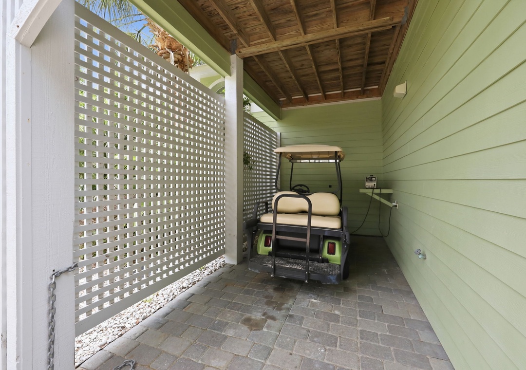 Covered parking area with latticed privacy screen and paver flooring—convenient golf cart storage adds easy mobility for local exploration.