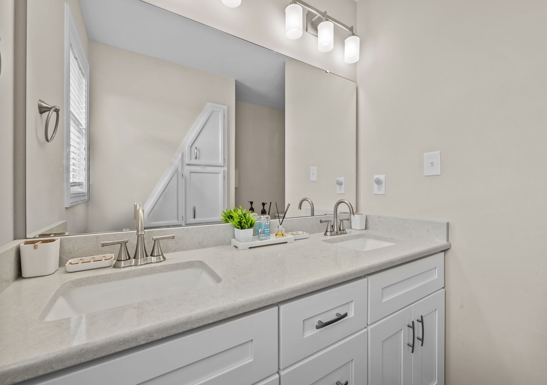 Refresh in your elegant dual-sink bathroom with pristine quartz counters and bright vanity lighting for perfect morning routines.