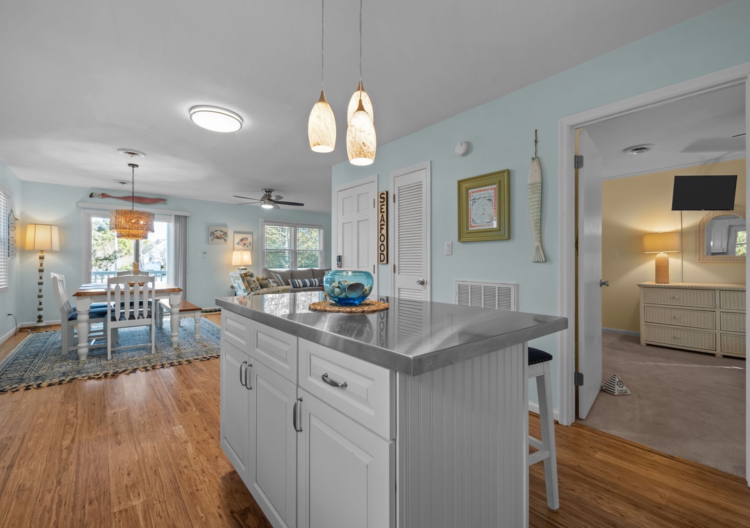 Your bright coastal kitchen flows into a cozy living space where aqua walls and warm wood floors create a beachy haven for cooking and relaxing together.