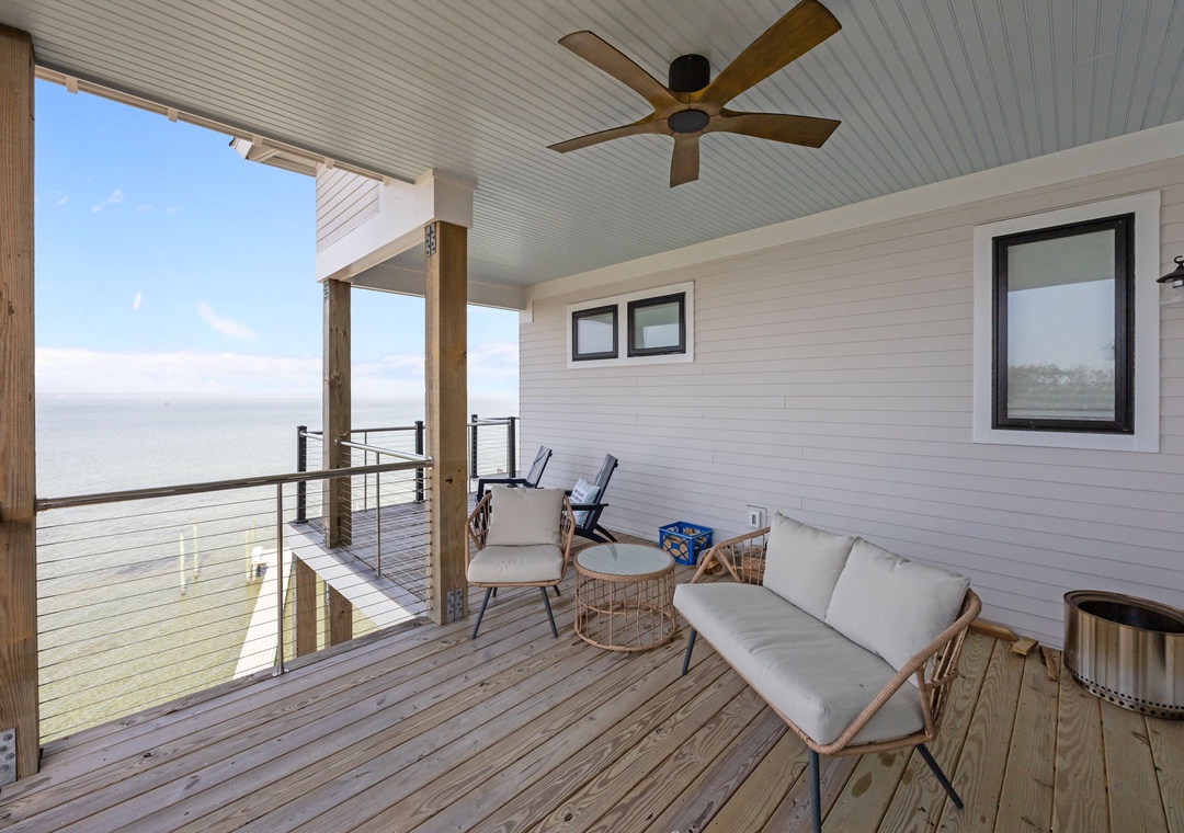 Relax on your private covered terrace with ocean views, featuring comfortable seating and a gentle ceiling fan for perfect outdoor lounging.