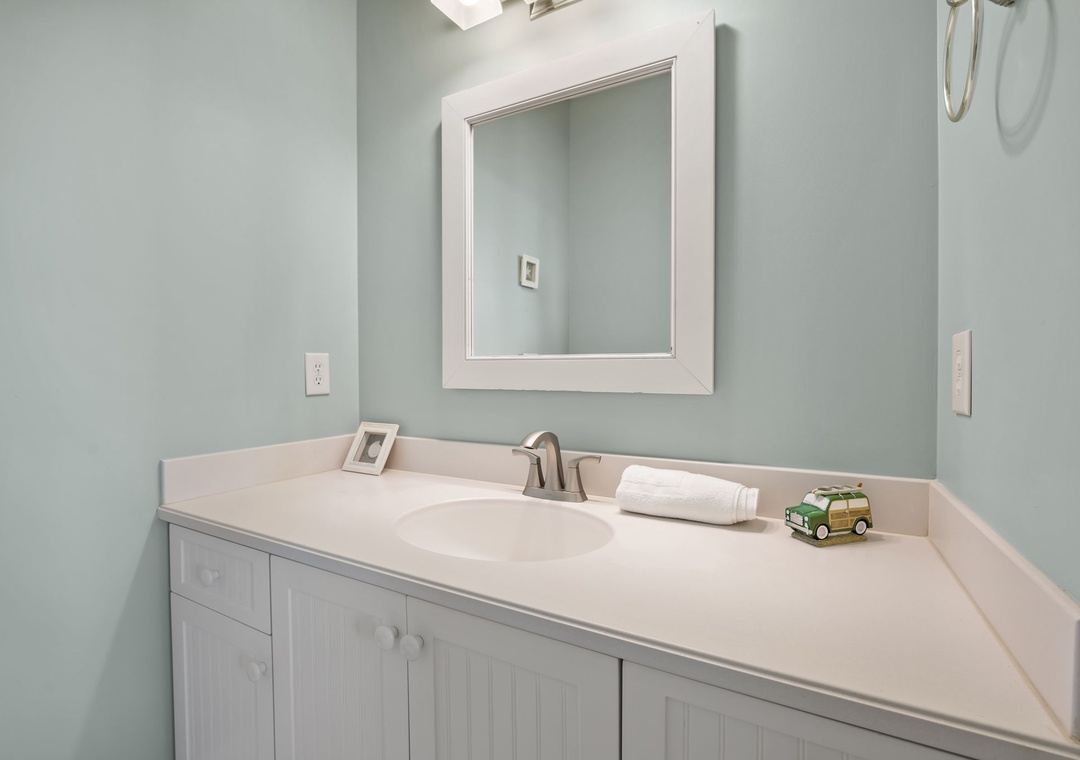 Refresh in your serene bathroom featuring soothing mint walls, crisp white vanity, and thoughtful amenities waiting for your arrival.