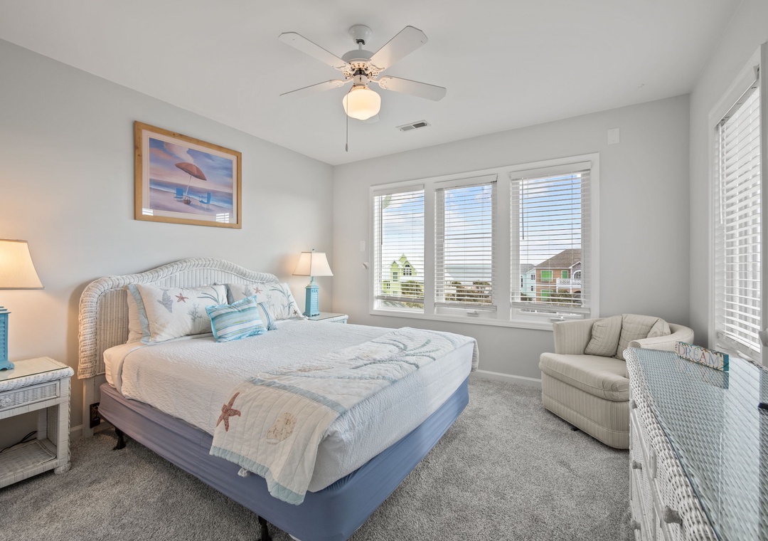 Drift off to sleep in your cozy coastal bedroom with ocean-themed decor and gentle ceiling fan breeze overhead.