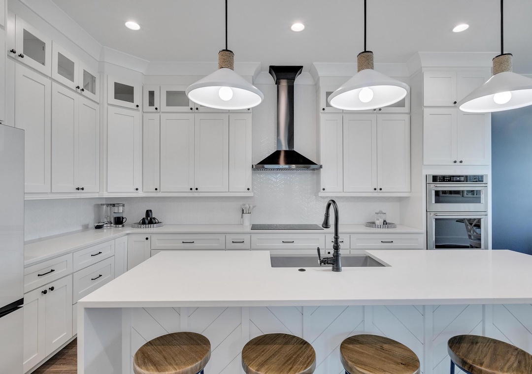 Gather around the spacious island and feel at home in this bright, chef-ready kitchen with gleaming countertops and warm pendant lighting overhead.
