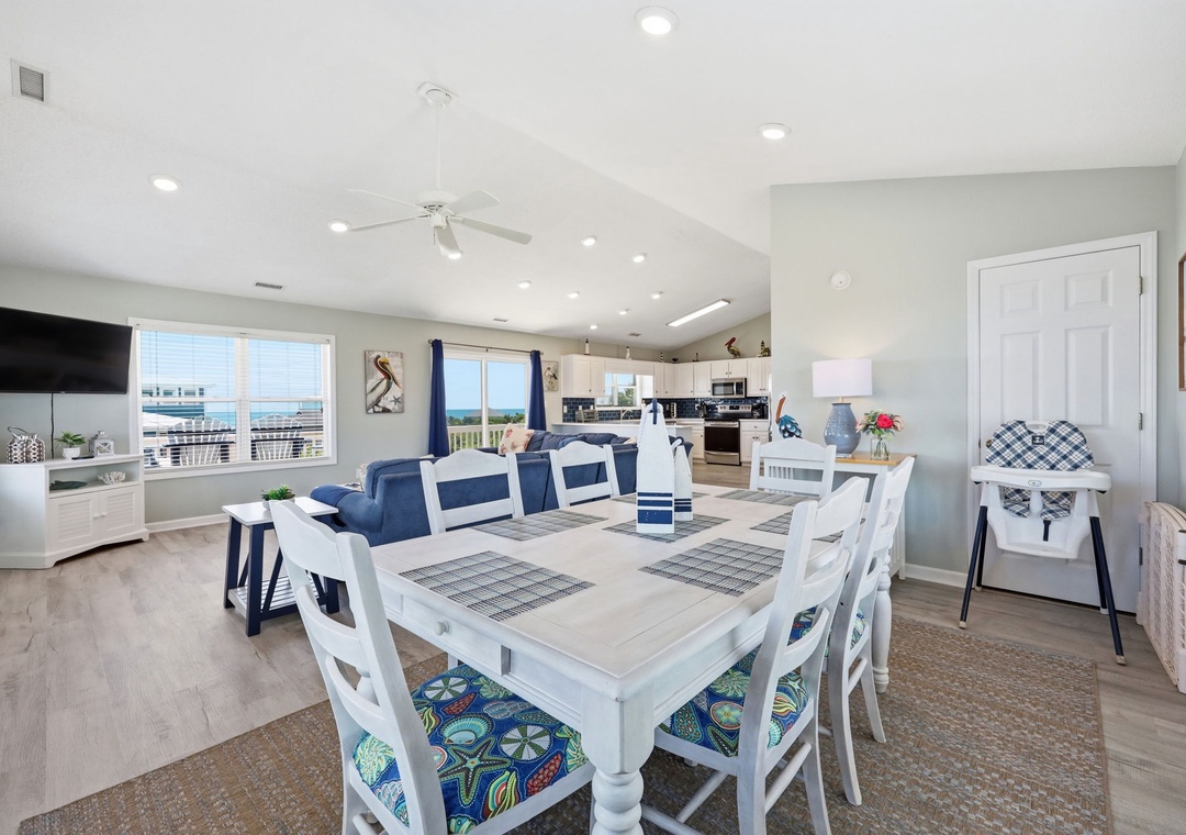 Gather around the spacious dining table with seating for eight, bathed in natural light from vaulted ceilings, as ocean breezes drift through this open-concept coastal retreat.