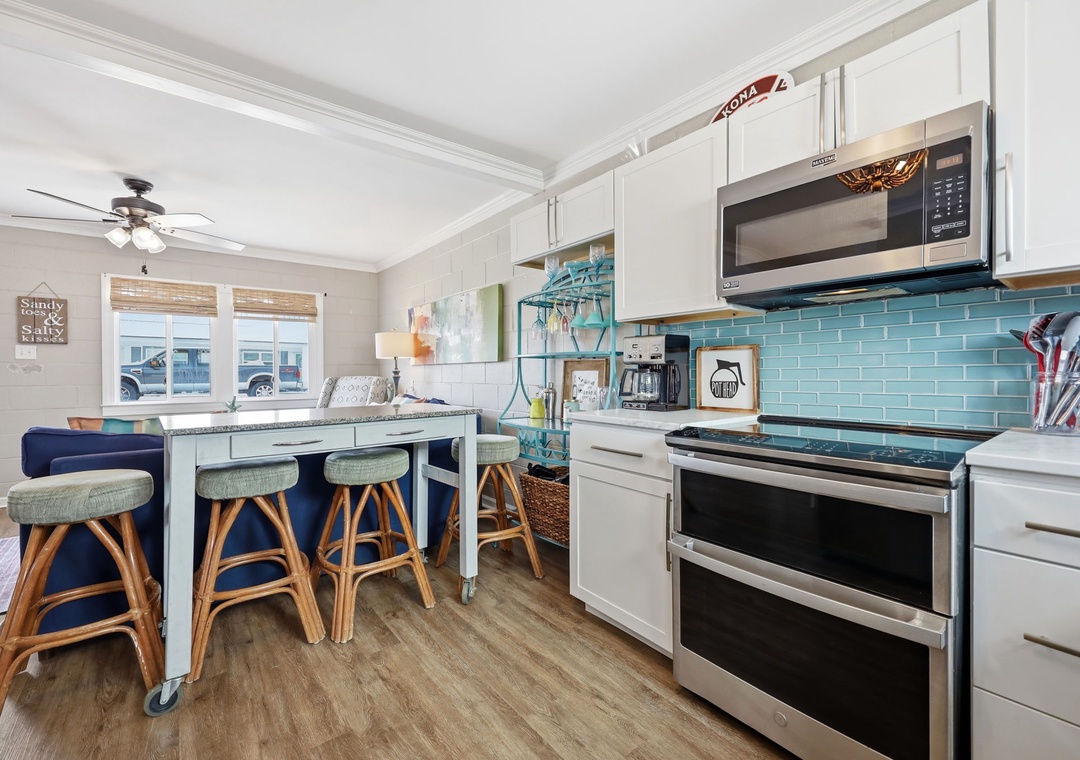 Picture yourself cooking in this bright coastal kitchen, complete with turquoise tile backsplash, stainless appliances, and a charming island where you can gather for meals and morning coffee together.