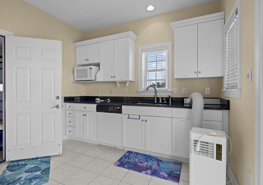 Step into your bright, fully-equipped kitchen featuring white cabinets, granite counters, and modern appliances for all your culinary adventures.