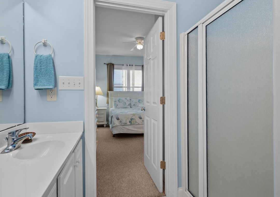 Step from your private bathroom into a peaceful bedroom retreat with soft coastal hues and comfortable bedding awaiting your arrival.