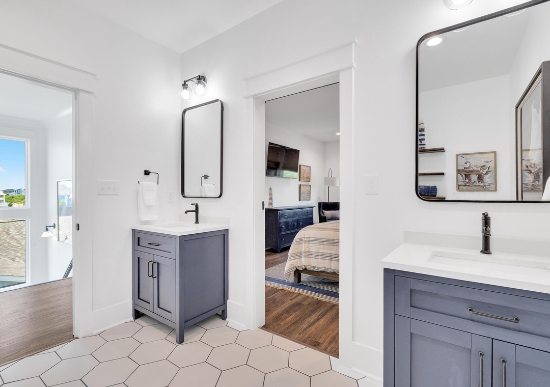 Your stylish dual-vanity bathroom features modern fixtures and chic hexagonal tile flooring, with a view into the serene bedroom and easy access to your private outdoor space.