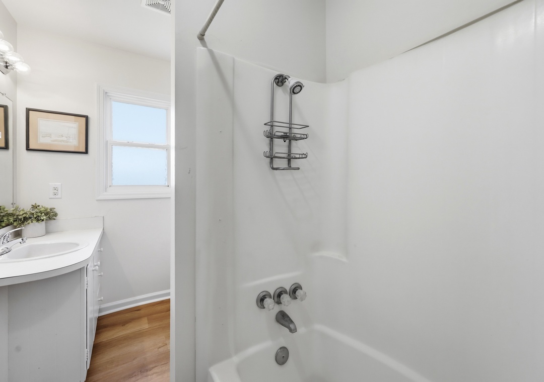 Spotless bathroom with a bright tub-shower combo, modern fixtures, and a clean white vanity that offers plenty of counter space for your essentials.
