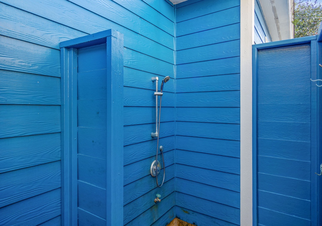 Rinse off after beach days in your private outdoor shower, surrounded by charming blue wood walls that create a refreshing coastal retreat.