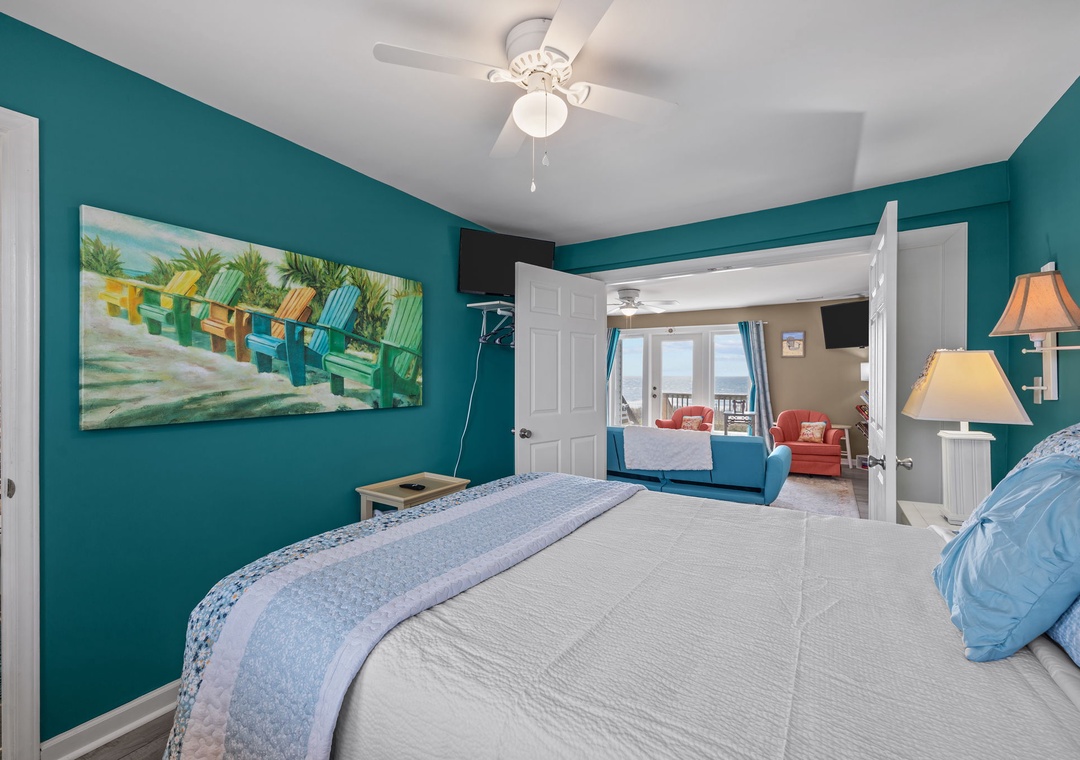 Your bright bedroom features vibrant turquoise walls and tropical artwork, with a ceiling fan keeping you cool and comfortable throughout your stay.