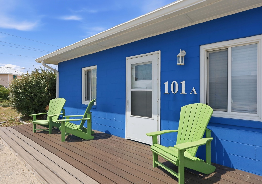 A vibrant blue-painted exterior marks unit 101A, featuring a welcoming deck with bright green Adirondack-style seating for outdoor relaxation.