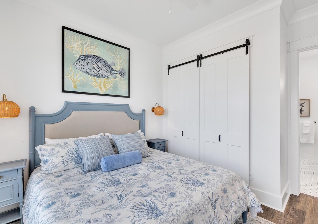 Drift off to sleep in this coastal-inspired bedroom featuring a charming barn door, soothing blue linens, and beachy décor that brings the ocean right to your doorstep.