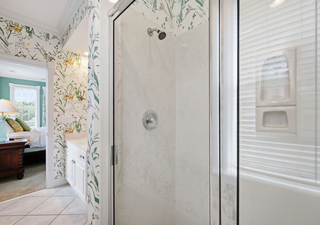 Step into your private bathroom, where botanical wallpaper brings nature indoors and a sleek glass-enclosed shower awaits your refreshing morning routine.