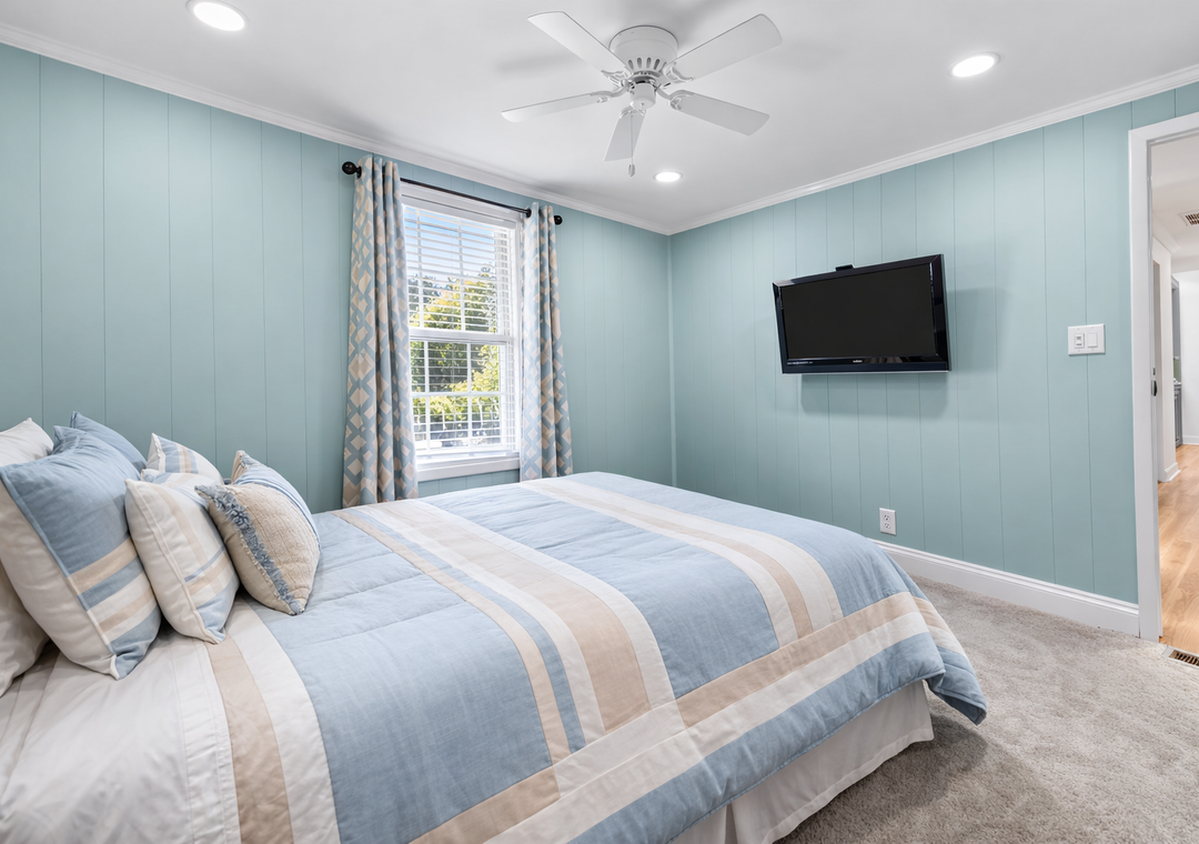 Drift off in this calming bedroom with soft blue hues, coastal bedding, and wall-mounted TV for your evening entertainment.