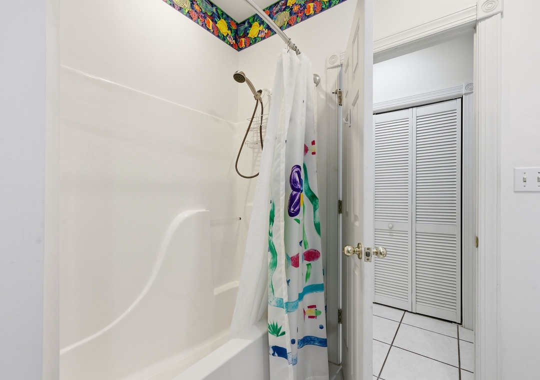 Freshen up in your clean, bright bathroom with a full tub-shower combo and playful tropical accents above, bringing a splash of island charm to your daily routine.