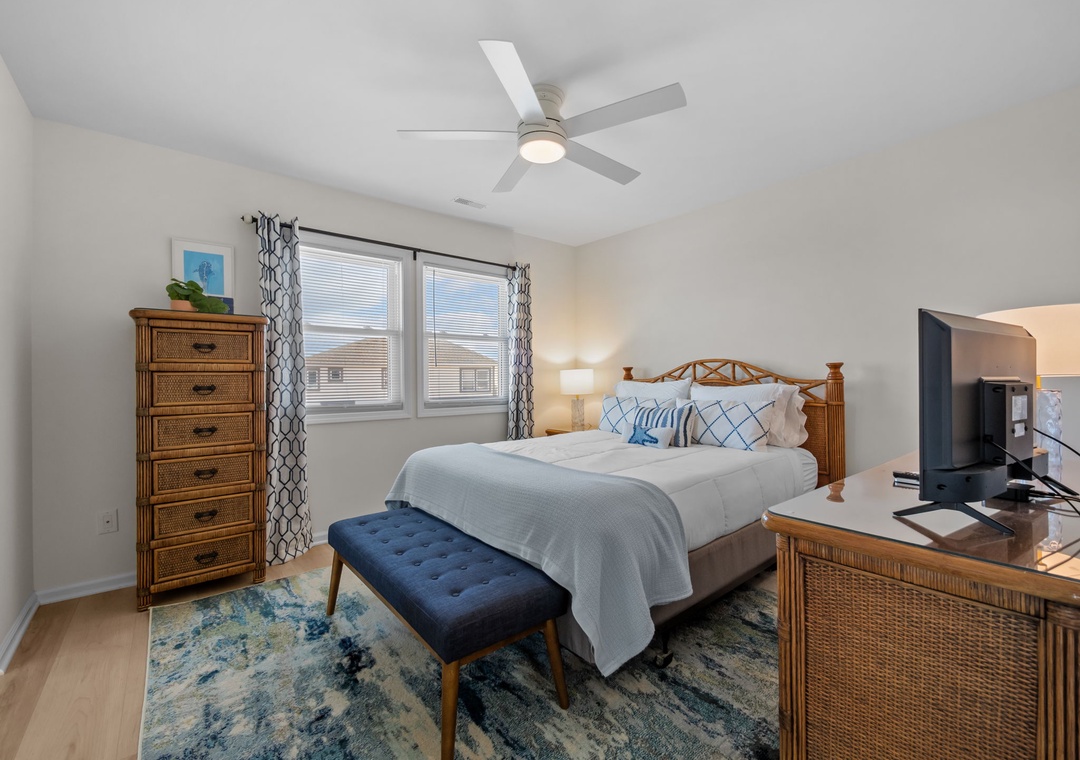 Unwind in your peaceful bedroom featuring coastal-inspired furnishings, a comfortable king bed, and gentle ceiling fan keeping you cool.