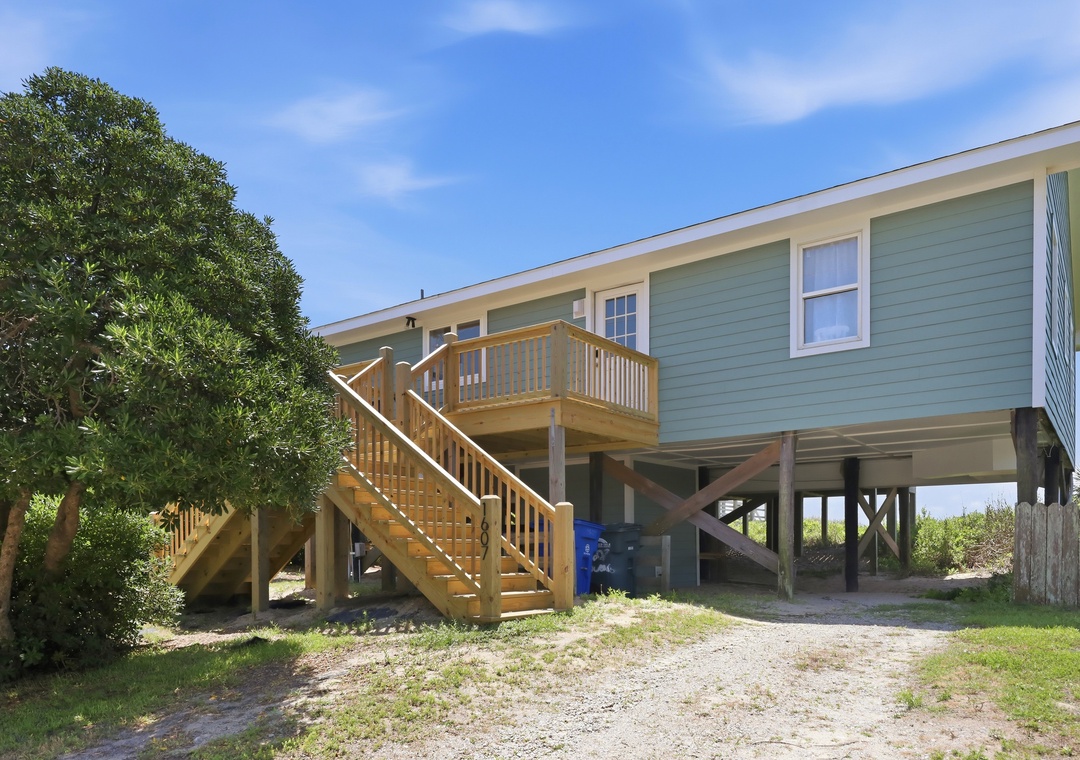 Elevated beachside retreat with covered parking and private deck, surrounded by coastal greenery and just steps from the shore.